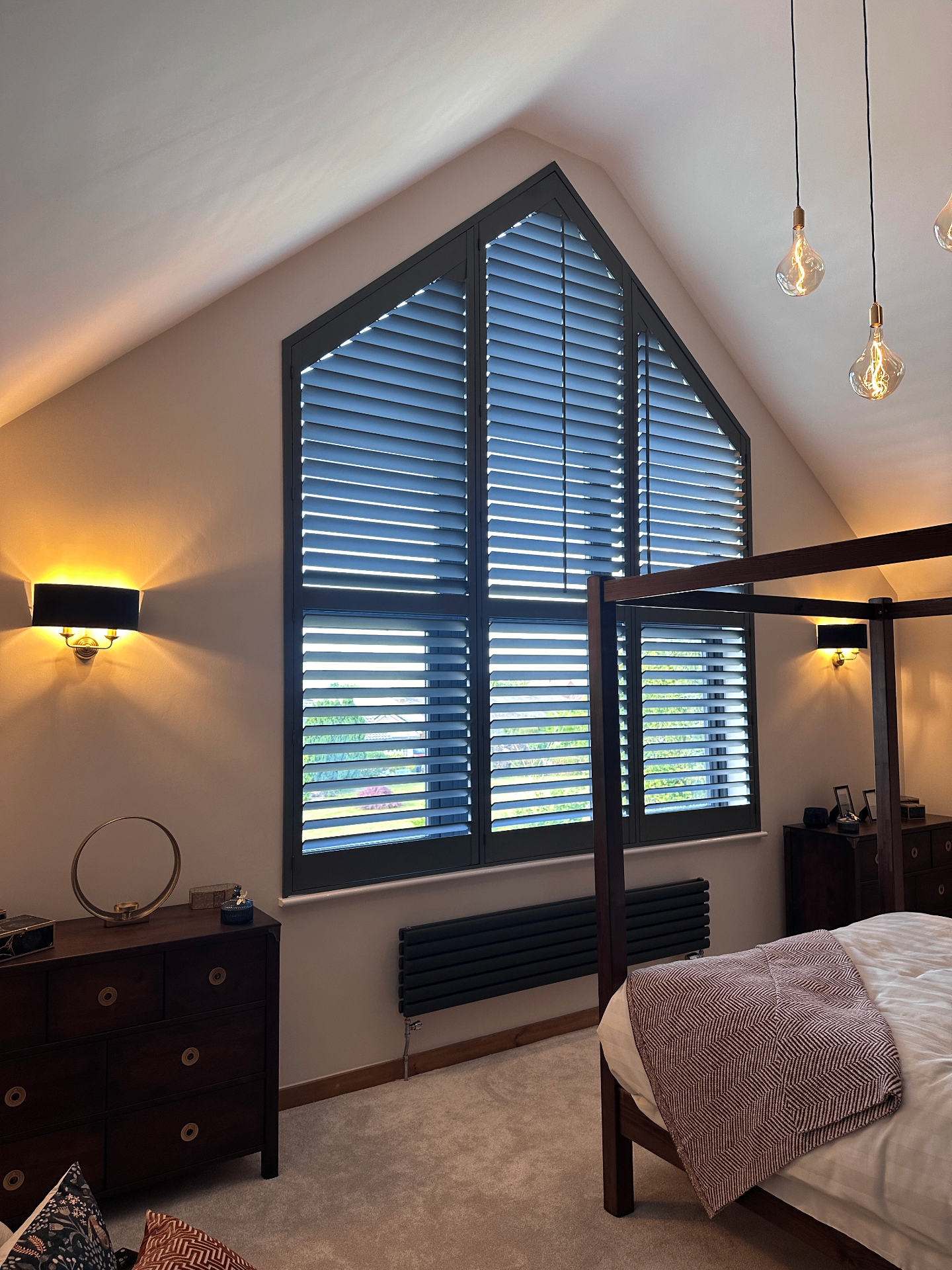 Dark bespoke shutters in an arched bedroom window
